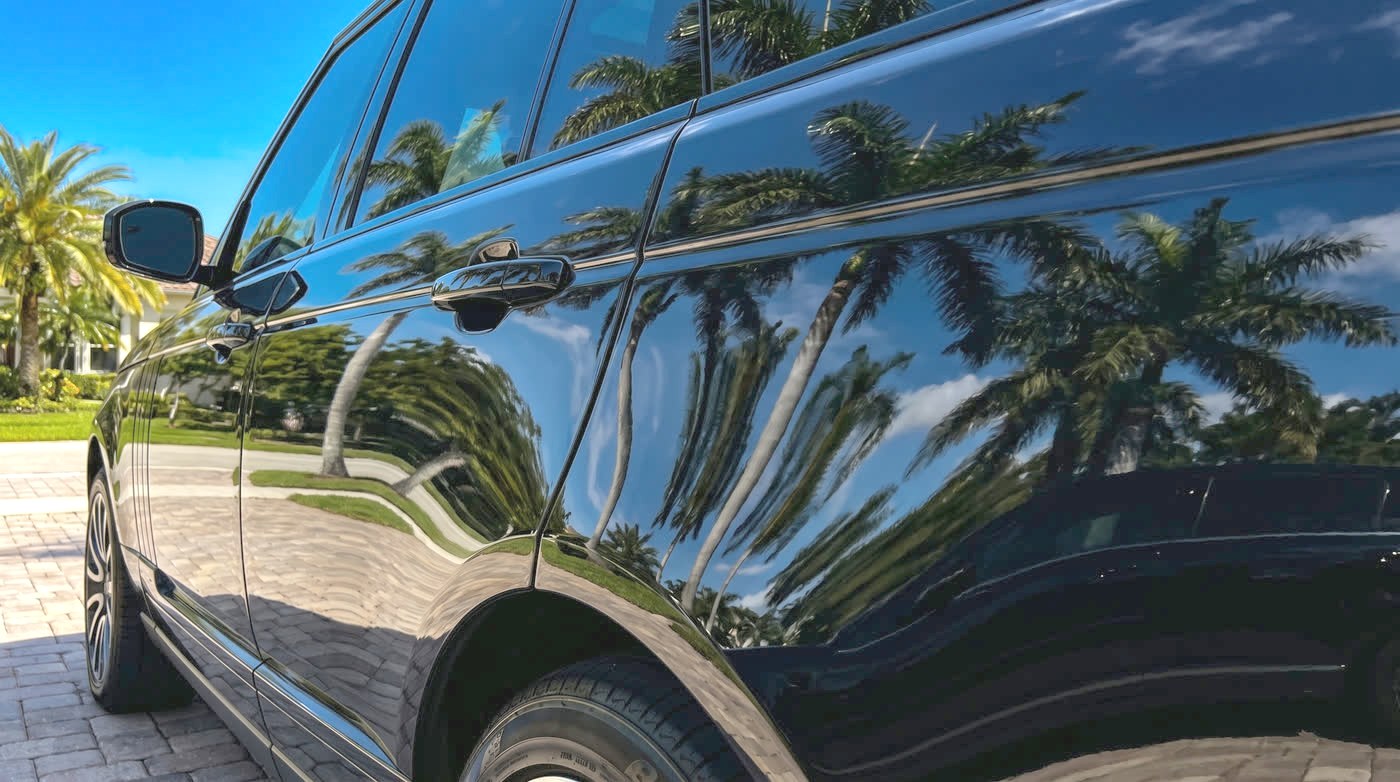 After: the same door with flawless paint, palm trees reflected in a perfect mirror finish.